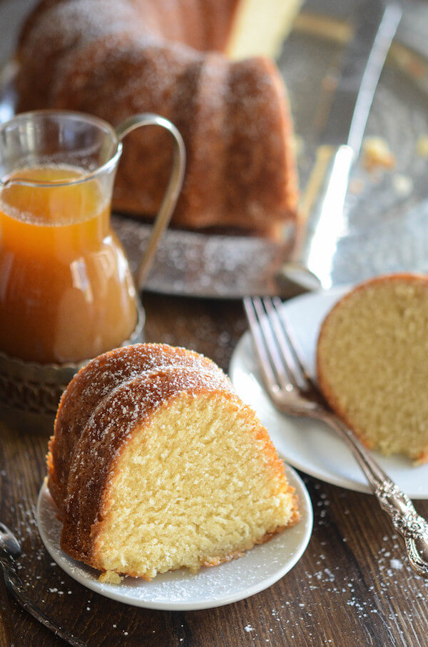 Tre fette di plumcake alle mandorle accanto a una caraffa di salsa all'amaretto