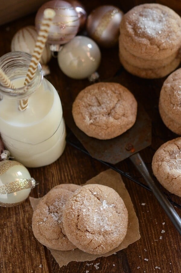 Stacks of spice cake cookies next to a tall glass of milk with straws.