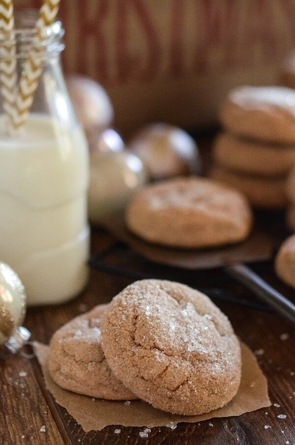 Stacks of spice cake cookies next to a tall glass of milk with straws.