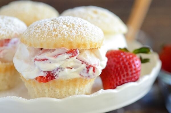 Cupcakes filled with strawberries and cream on a cake stand garnished with a fresh strawberry.