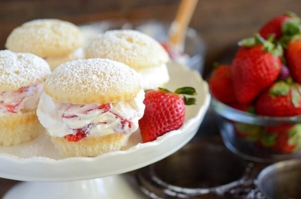 Strawberries and cream cupcakes on a cake stand garnished with a fresh strawberry.