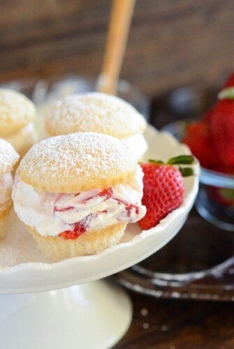 Strawberries and cream cupcakes on a cake stand garnished with a fresh strawberry.