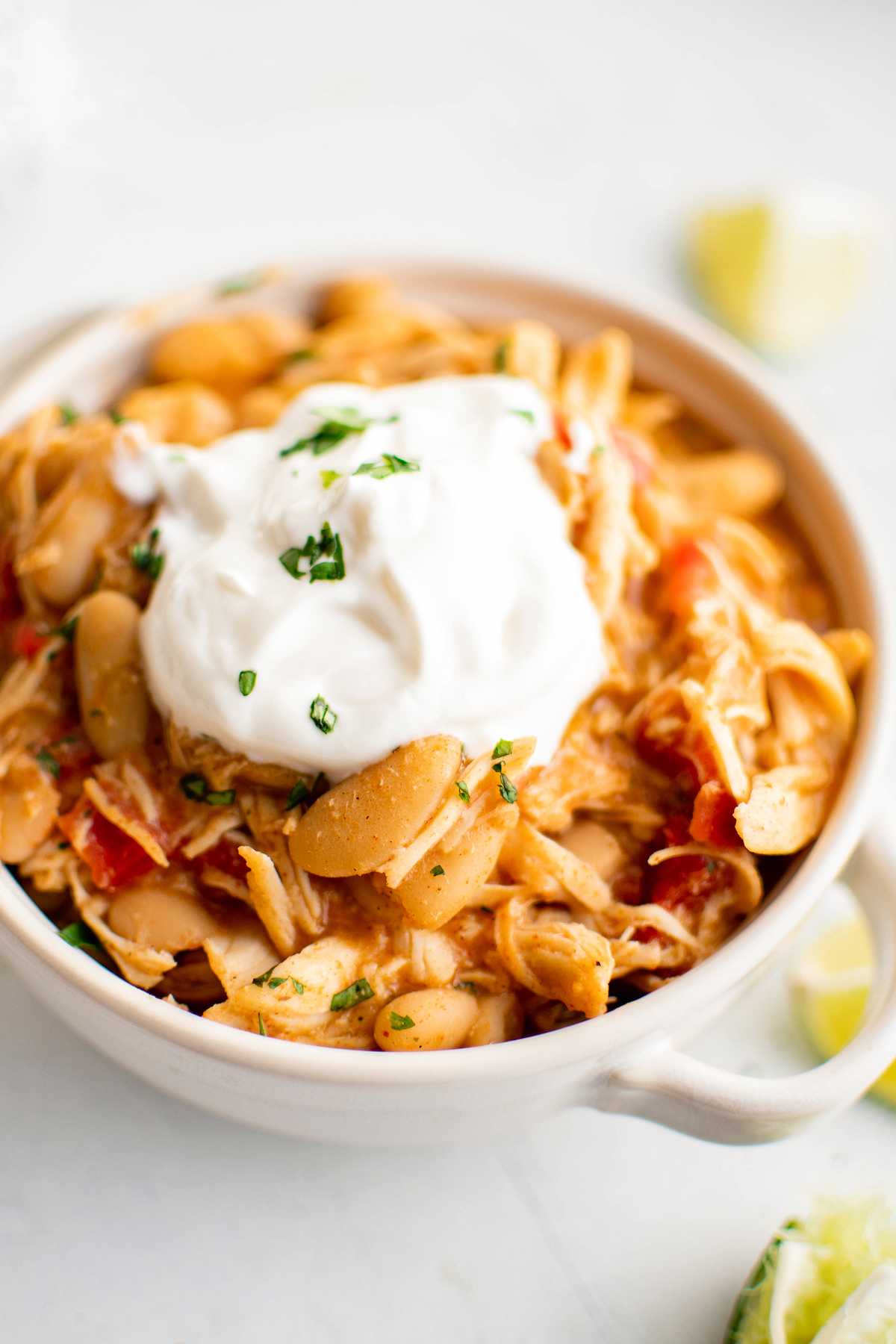 A bowl of crockpot white chicken chili topped with sour cream.