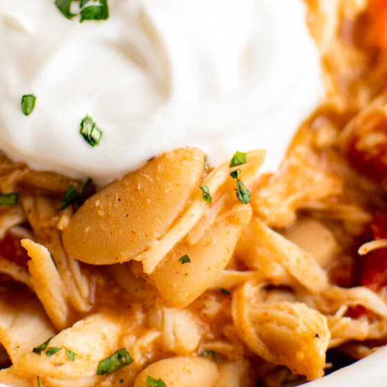 Close up of a bowl of taco ranch chicken chili topped with sour cream.