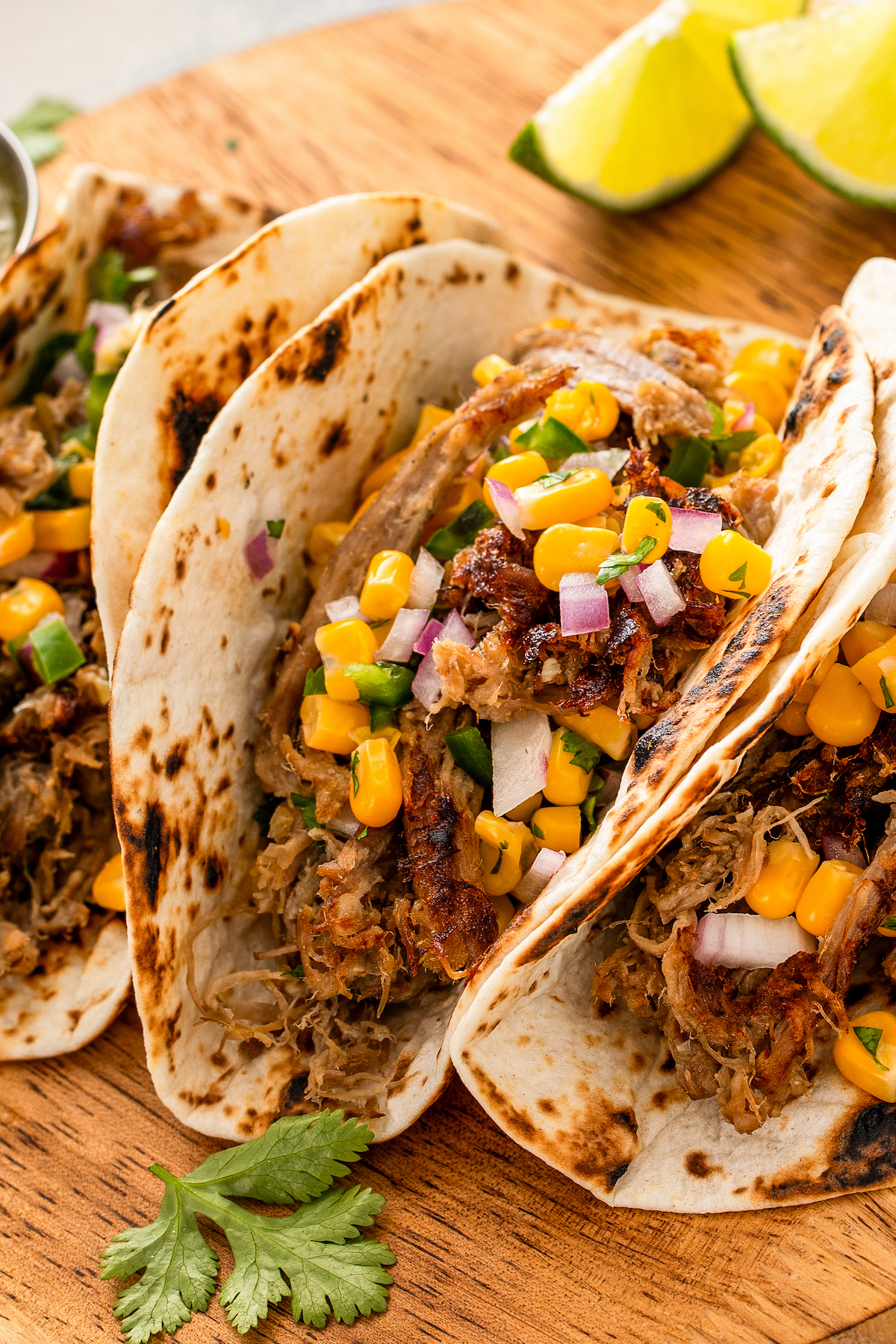 Tacos with slow cooker carnitas, corn salsa, and red onions. 