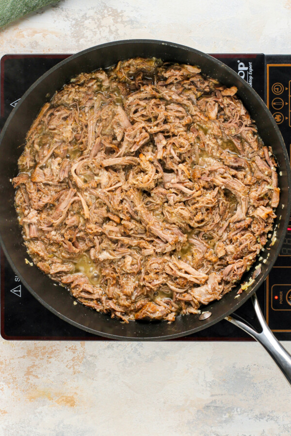 Adding the shredded pork to the pan. 