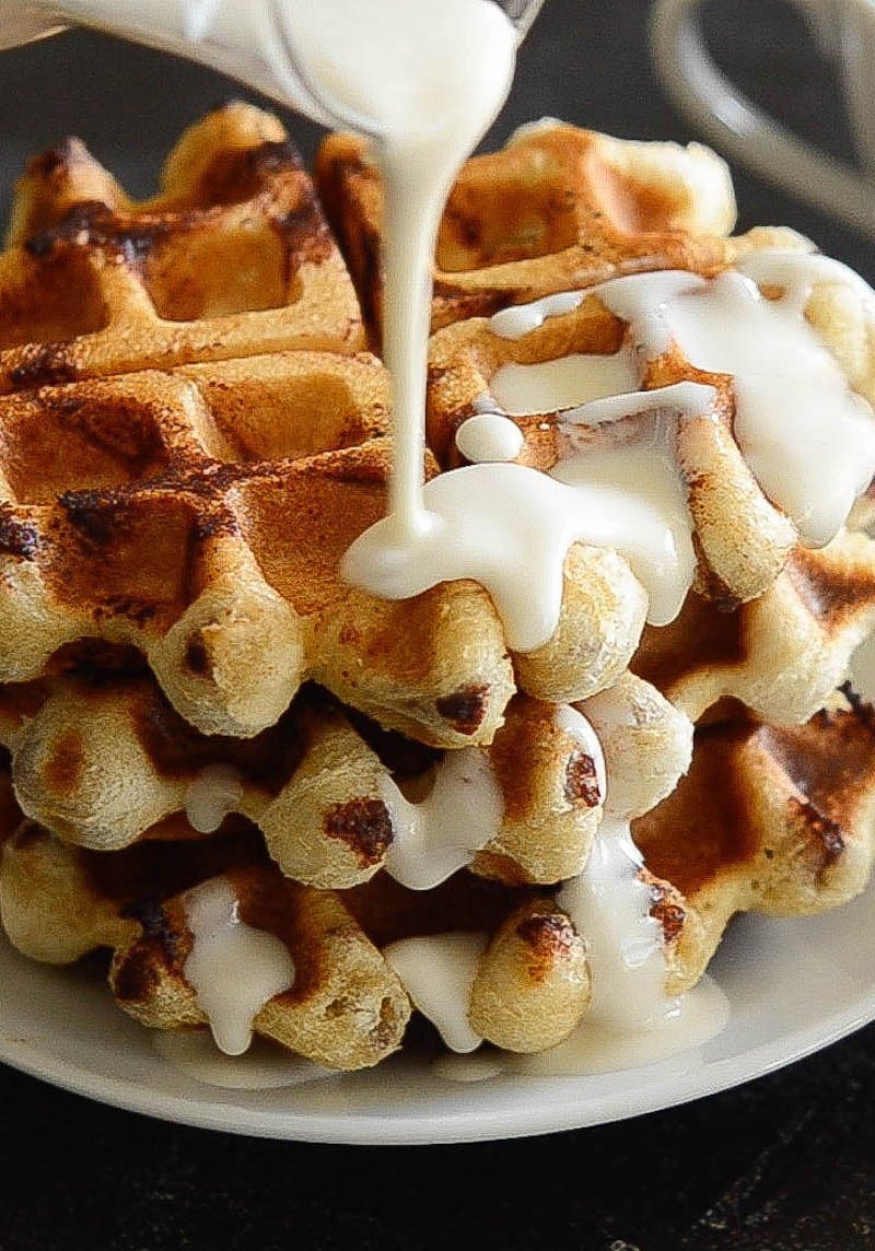 Maple Cream Cheese Syrup Being Poured over a Stack of Waffles on a Plate