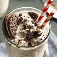 Crushed oreos on top of a cookies and cream milkshake.