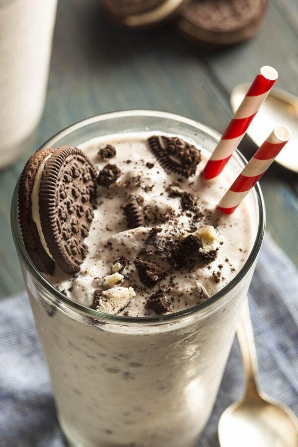 Crushed oreos on top of a cookies and cream milkshake.