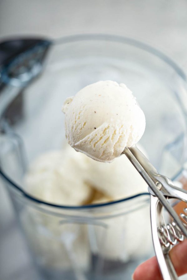 Vanilla ice cream being scooped into a blender.