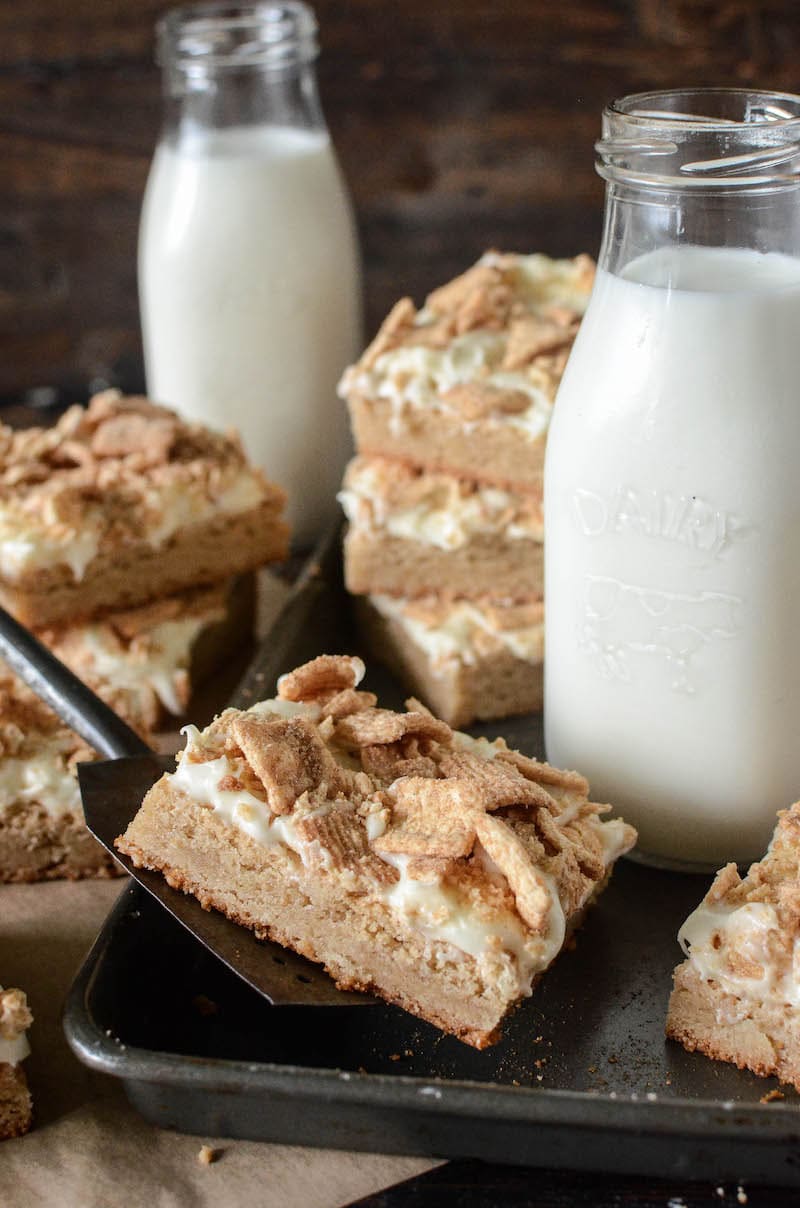 A Pan Filled with Cinnamon Toast Crunch Bars and a Tall Glass of Milk with More Bars and Milk in the Background