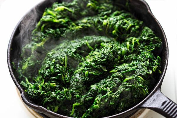 Frozen spinach in a skillet being thawed.