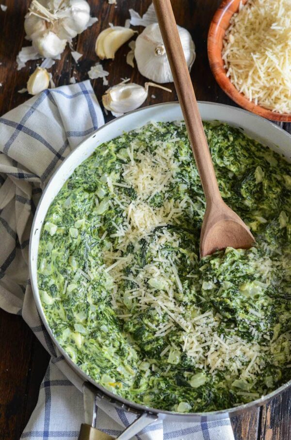 Creamed Spinach in a large skillet with a wooden spoon.