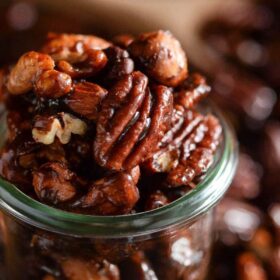 A close up of pumpkin spice candied nuts in a glass jar.