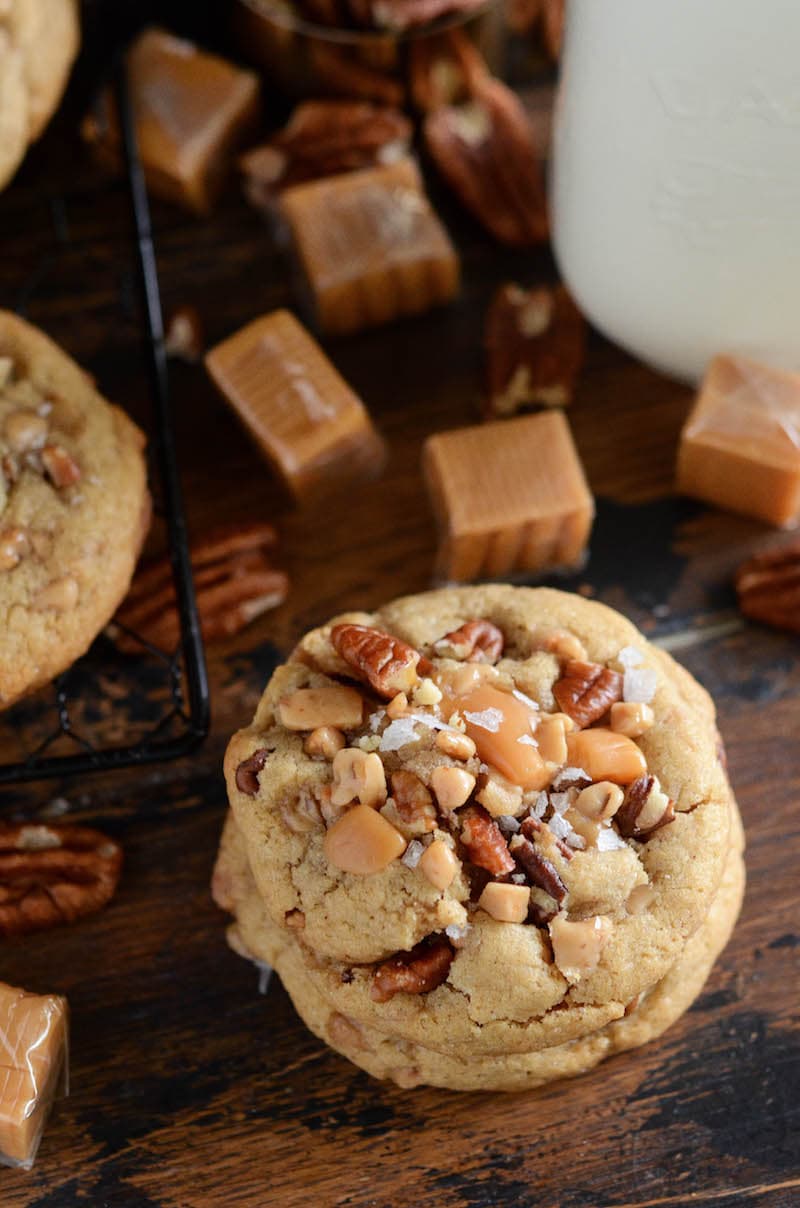 Salted caramel crunch cookies next to scattered caramels and toffee bits.