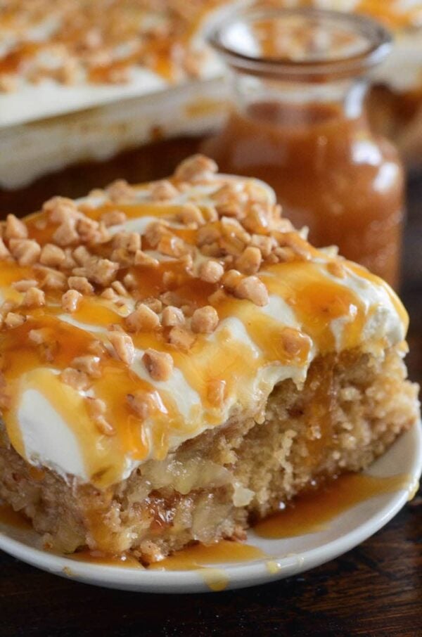 Caramel Apple Toffee Cake: a homemade - from scratch - poke cake is filled with bites of apple, toffee, caramel sauce and topped with sweet whipped cream!