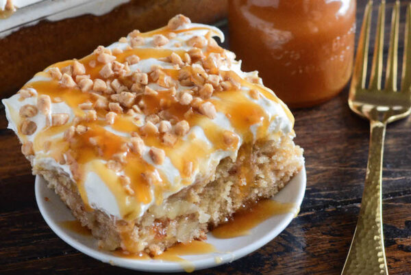 Caramel Apple Toffee Cake: a homemade - from scratch - poke cake is filled with bites of apple, toffee, caramel sauce and topped with sweet whipped cream!