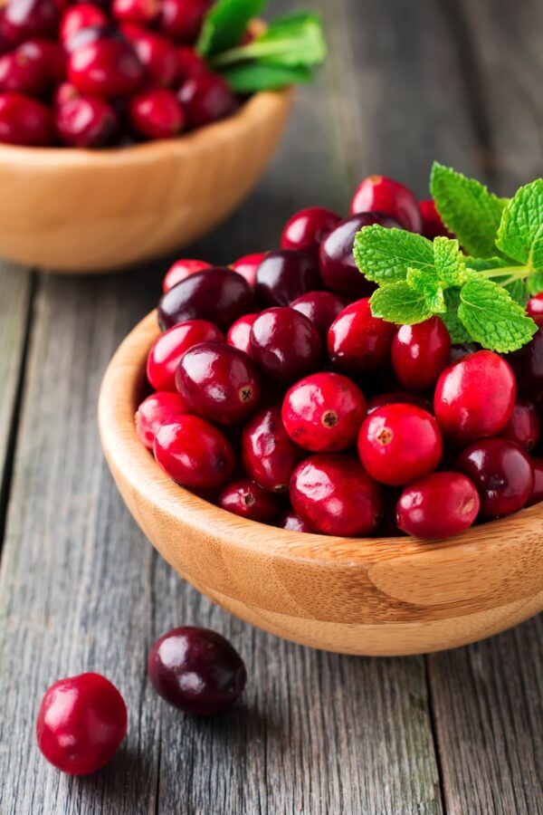 Fresh tart cranberries in a brown wooden bowl.