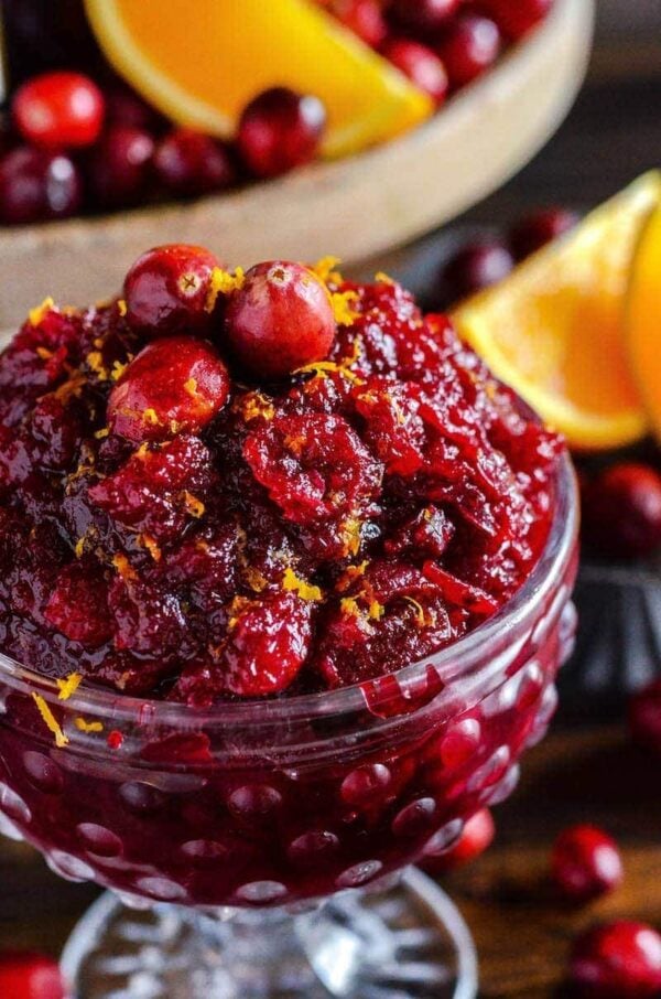 Cranberry Orange Relish in a crystal bowl topped with fresh cranberries and orange zest. 