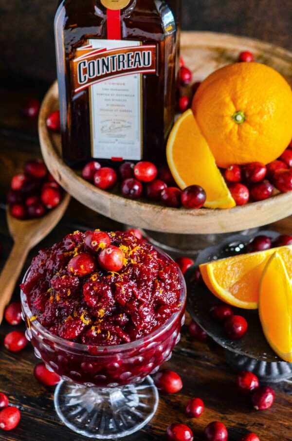 Cranberry relish in a clear bowl with other fresh ingredients surrounding it. 