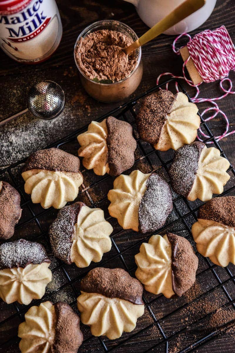 Malted Shortbread Cookies on a Metal Cooling Rack Beside a Jar of Cocoa Powder and Christmas Twine