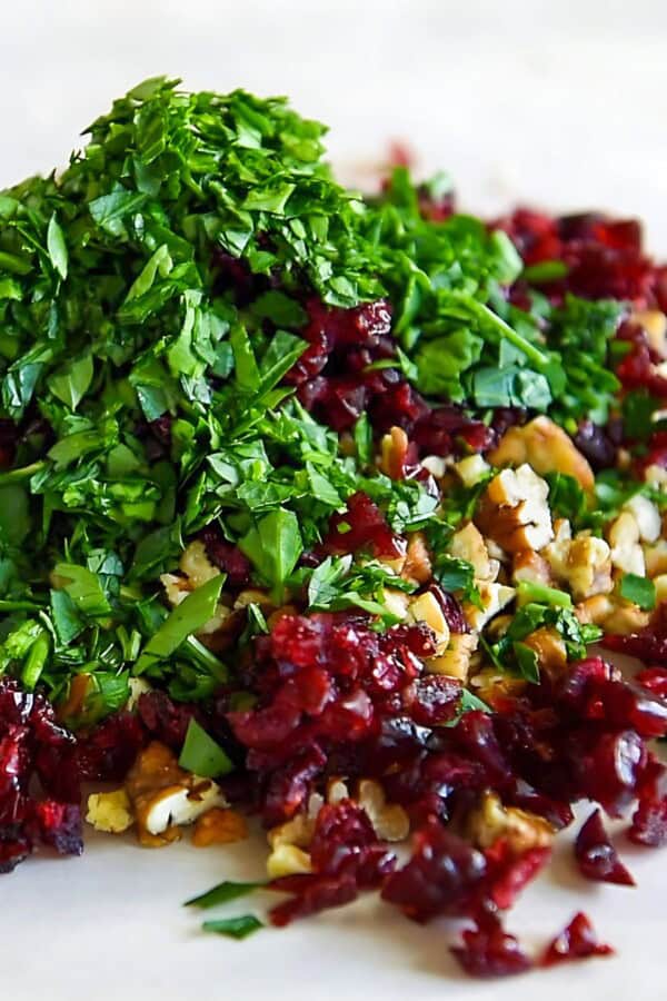 Fresh parsley, dried cranberries and pecans in a pile.