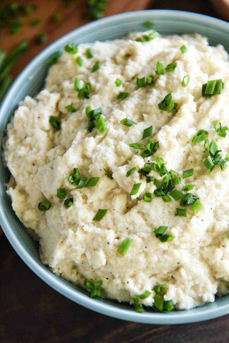 A bowl of roasted garlic cauliflower mash topped with chopped chives