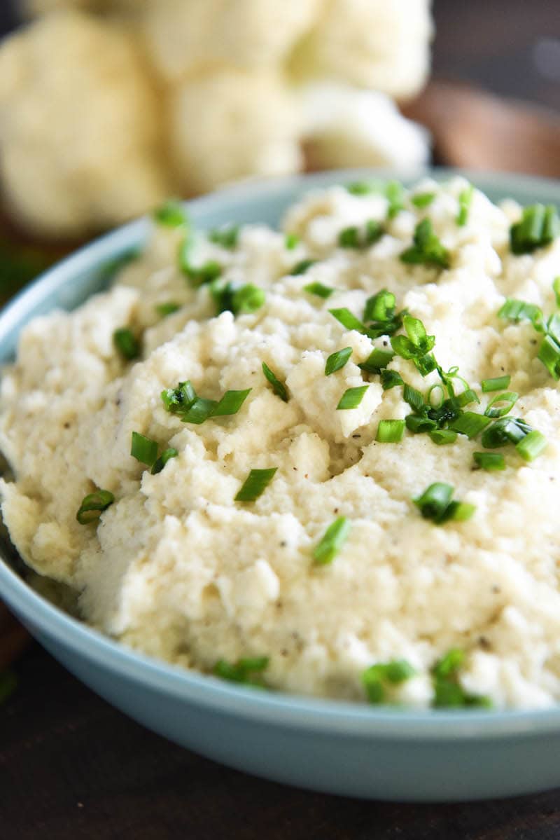 A close up of delicious and creamy roasted garlic cauliflower mash topped with chives