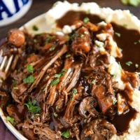 Slow Cooker Pot Roast in crockpot on a plate with mashed potatoes.