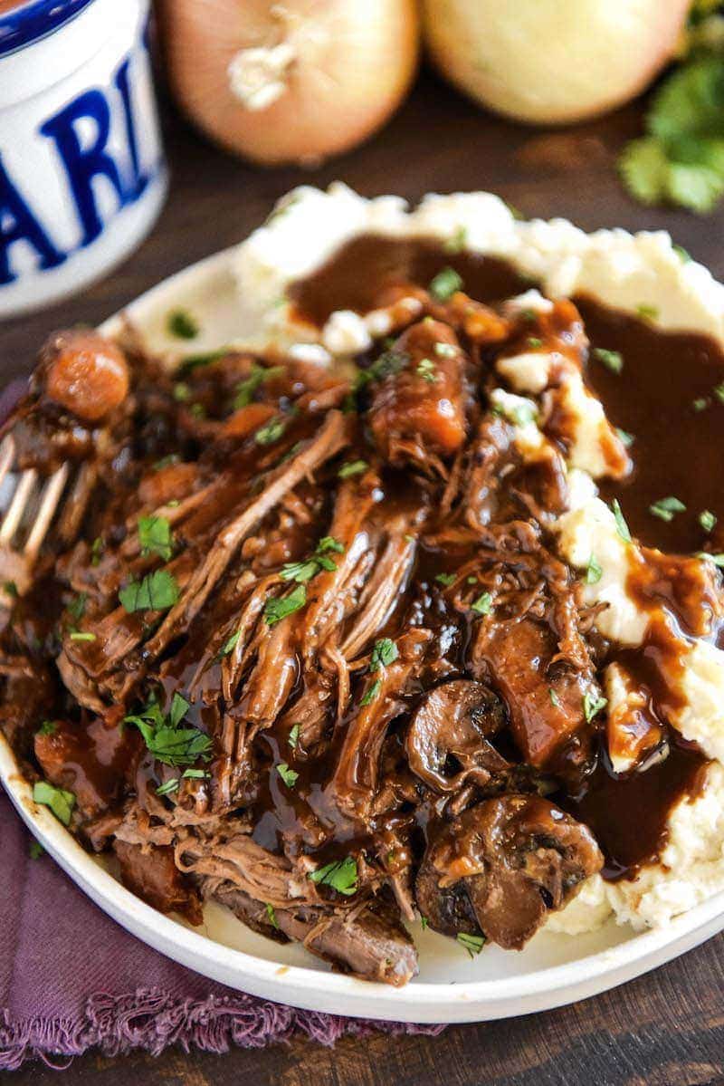 Slow Cooker Pot Roast in crockpot on a plate with mashed potatoes.