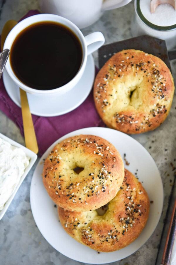 Overview image of Keto Bagels on a tray with a cup of coffee, cream cheese and a napkin. 