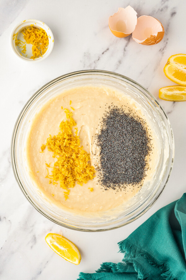 Adding zest and poppy seeds to a bowl of lemon batter.
