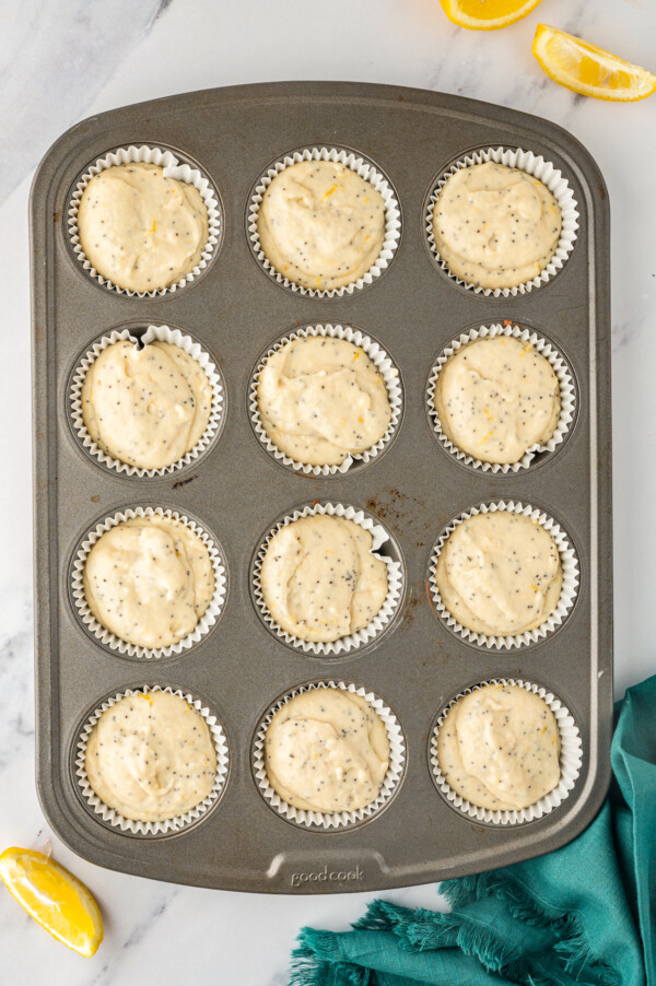 A muffin tin with paper liners filled with batter.