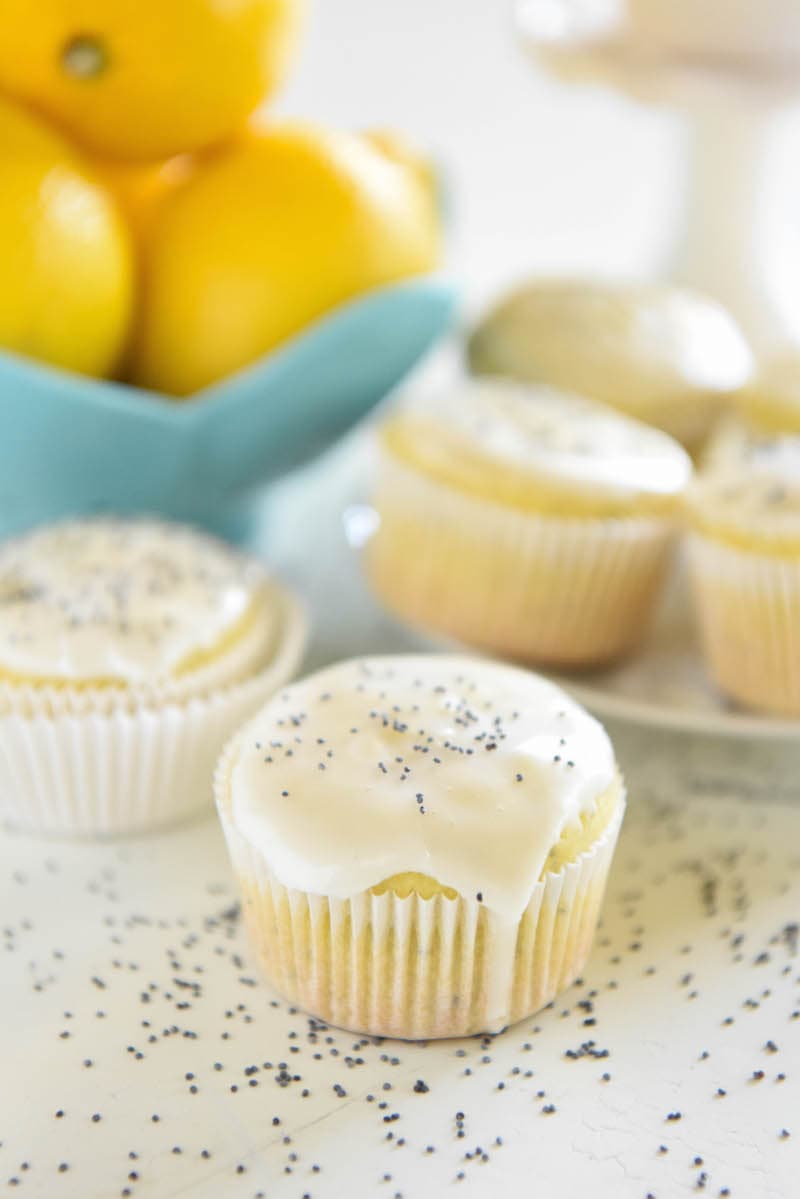A Lemon Poppy Seed Muffin on a Countertop with Lemon Glaze Dripping Down the Side