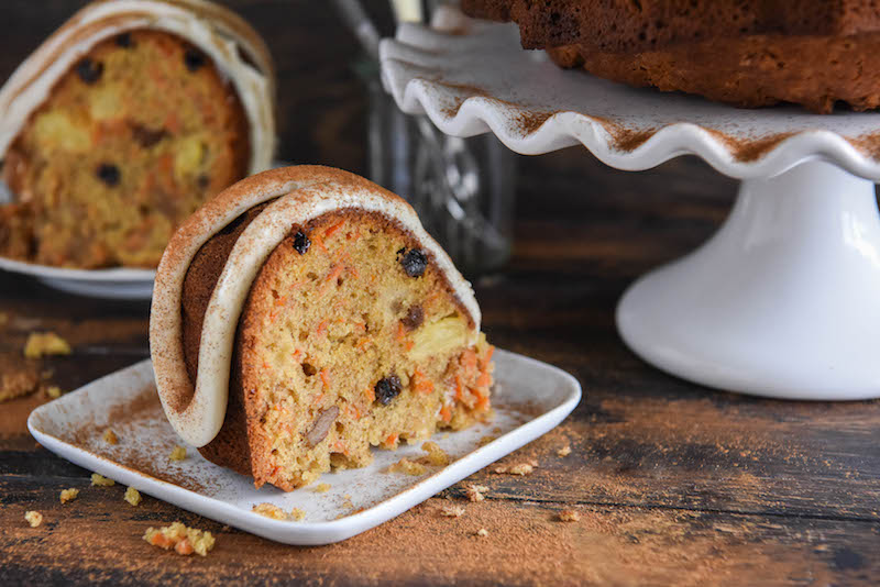 A Piece of Carrot Bundt Cake Beside Another Slice and the Rest of the Cake on a Cake Stand