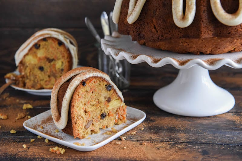 Two Slices of Carrot Cake on a Table Beside the Whole Cake