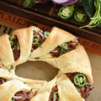 Pulled pork in a crescent ring dough with fresh vegetables in the background