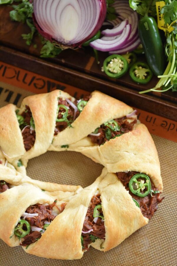 Pulled pork in a crescent ring dough with fresh vegetables in the background