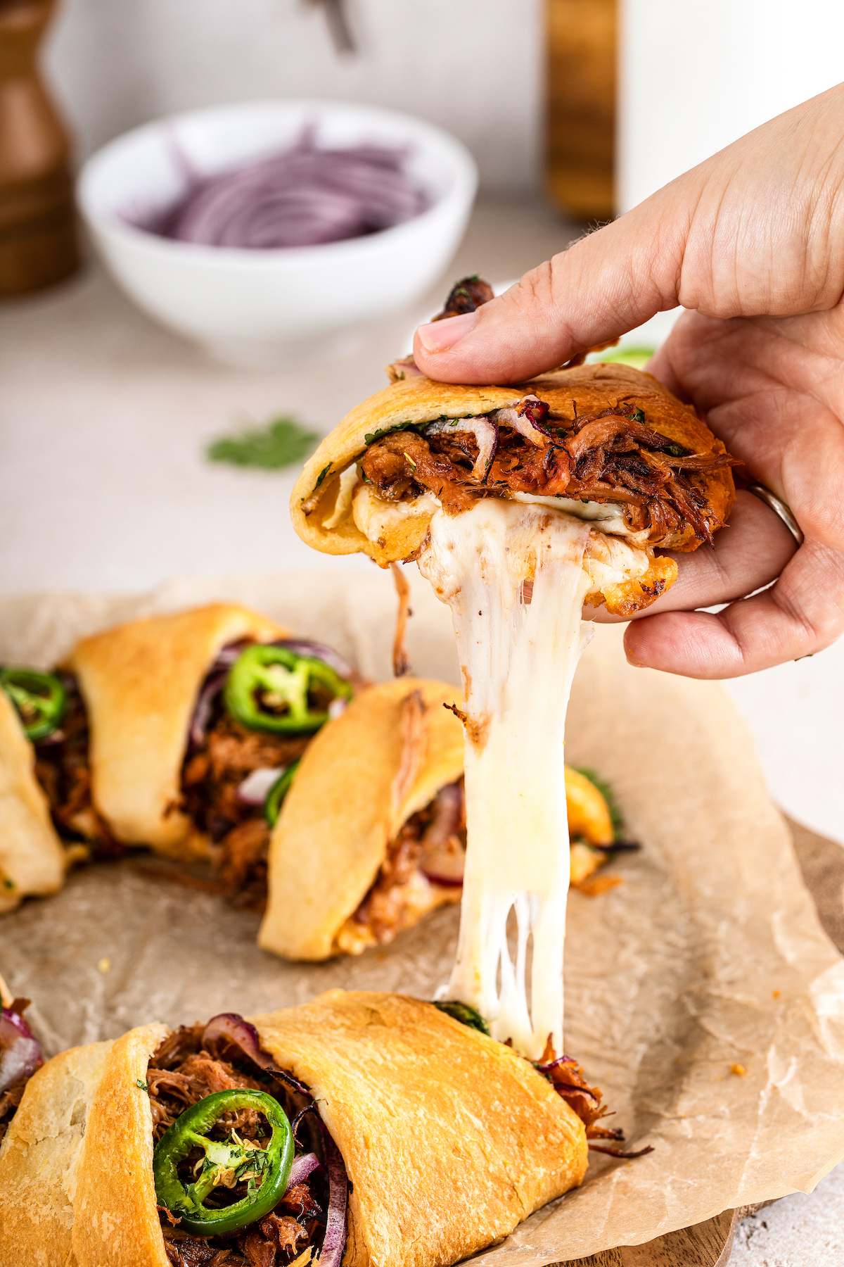 Slice of pulled pork appetizer with a cheese pull.