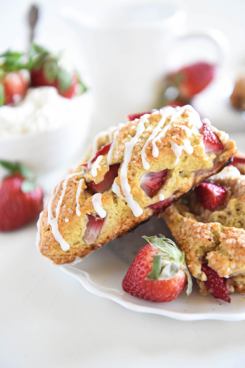 Strawberry shortcake scones on a white plate surrounded by fresh strawberries.