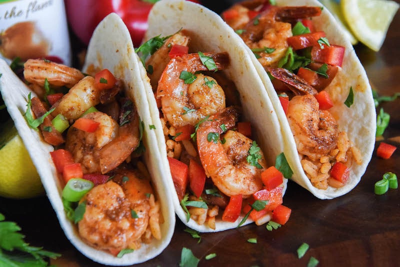 Landscape photo of three cajun shrimp tacos with toppings.