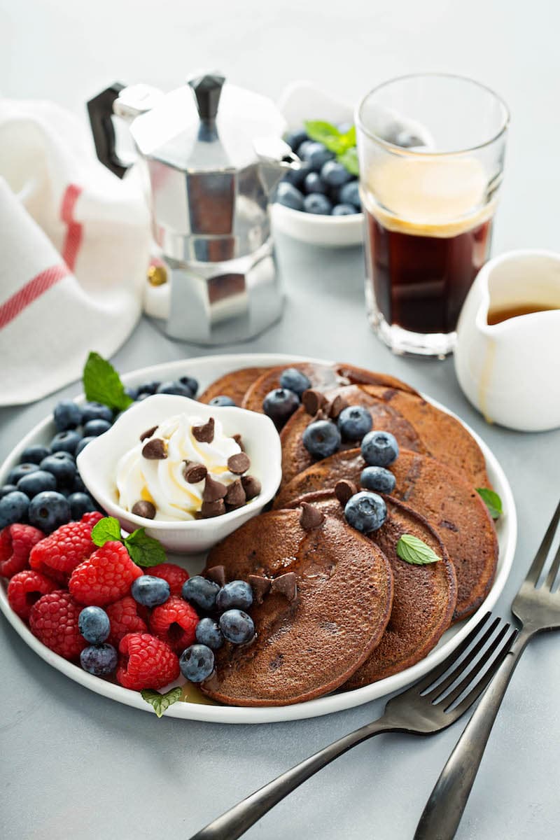 A Plate of Low Carb Pancakes with Berries and Cream Beside Two Forks