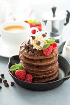 A Tall Stack of Low Carb Chocolate Chip Pancakes in a Crock with Whipped Cream and Syrup on Top