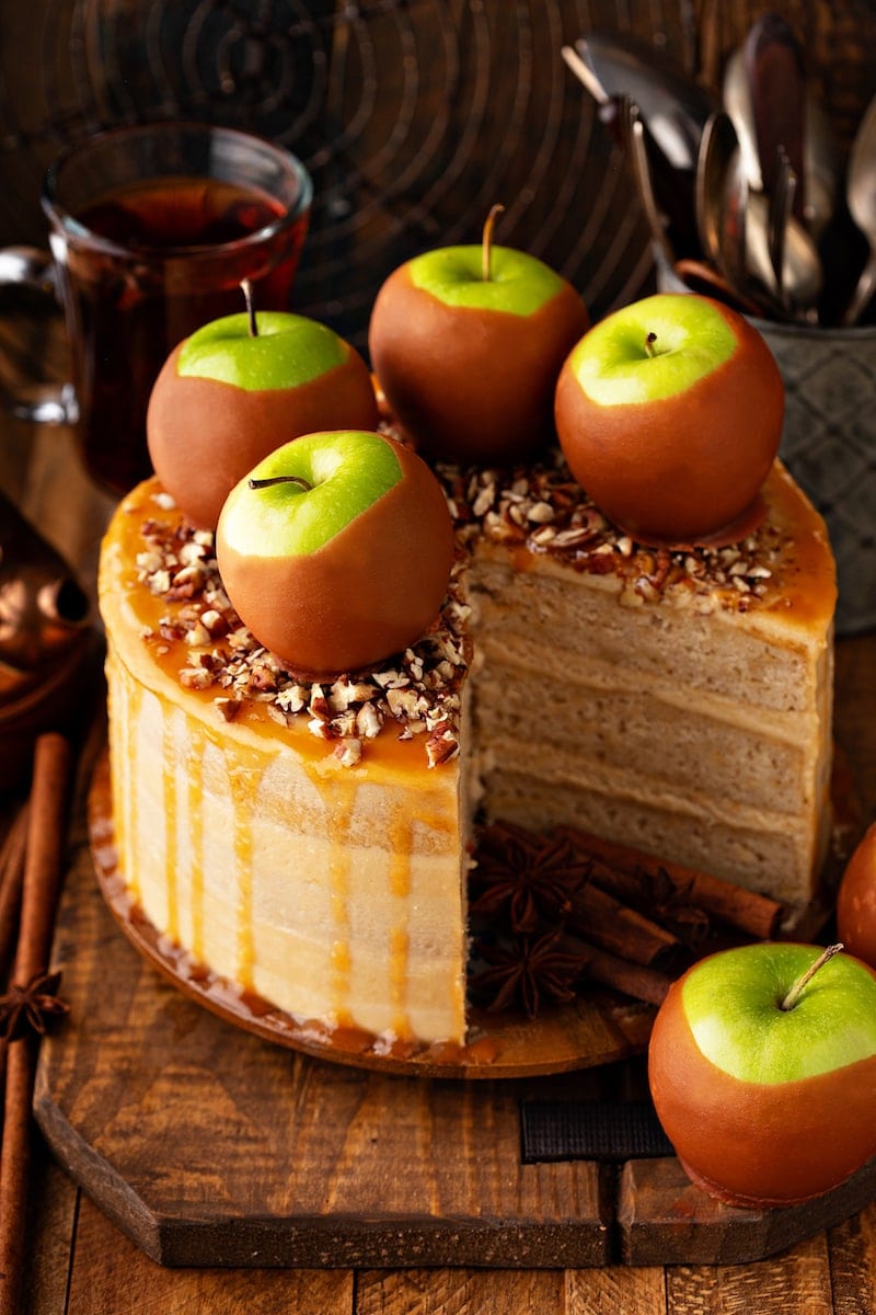 Three-layer caramel apple cake with pecans, salted caramel sauce, and caramel apples on top. 