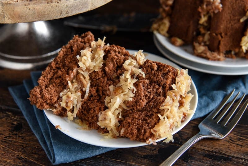 A Piece of Chocolate Cake with Pecan Coconut Frosting on a White Plate