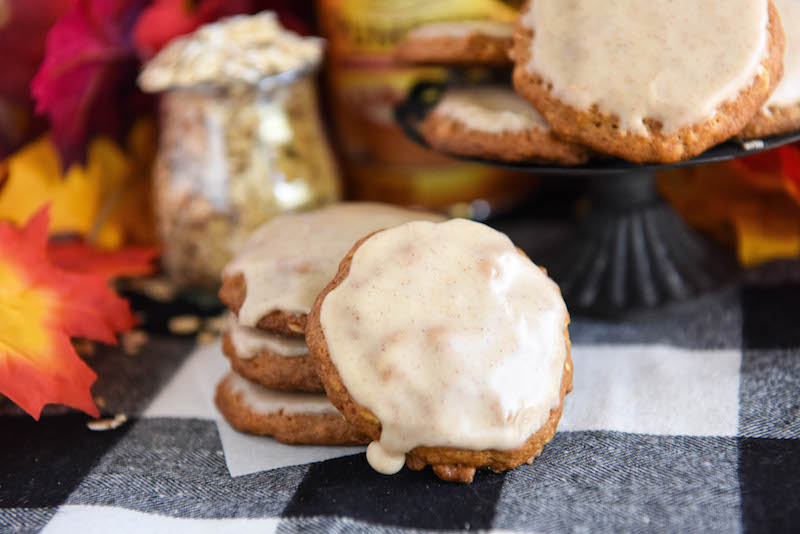 Iced pumpkin oatmeal cookies on display, surrounded by decorative fall leaves