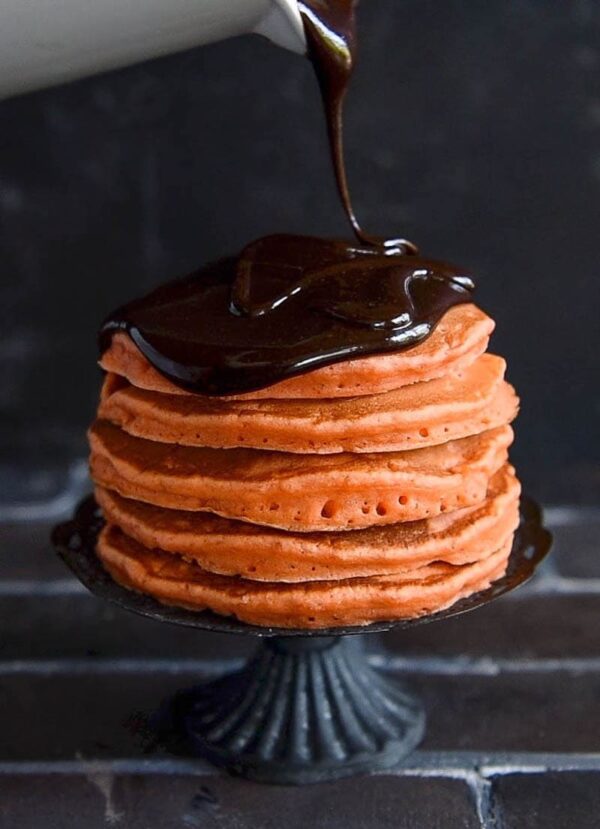 Halloween Ghost Pancakes: a big stack of homemade orange pancakes are topped with dark chocolate ganache and whipped cream ghosts for a spooky Halloween treat! #Halloween #Breakfast #Pancakes