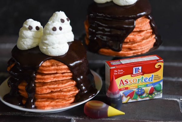 Halloween Ghost Pancakes: a big stack of homemade orange pancakes are topped with dark chocolate ganache and whipped cream ghosts for a spooky Halloween treat! #Halloween #Breakfast #Pancakes