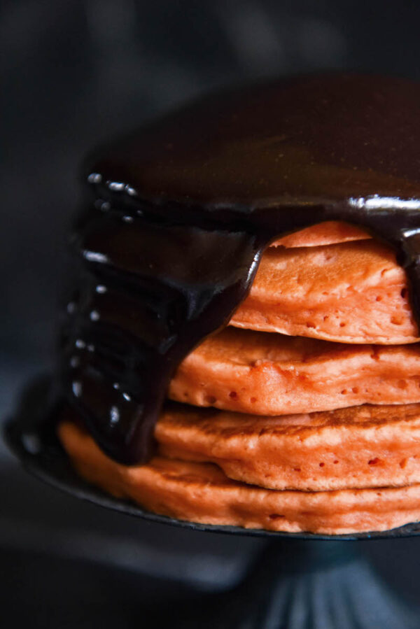 Halloween Ghost Pancakes: a big stack of homemade orange pancakes are topped with dark chocolate ganache and whipped cream ghosts for a spooky Halloween treat! #Halloween #Breakfast #Pancakes