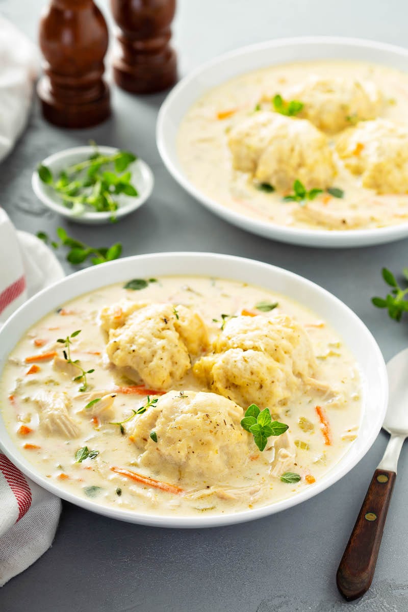 Two bowls of chicken and dumplings with fluffy drop dumplings.